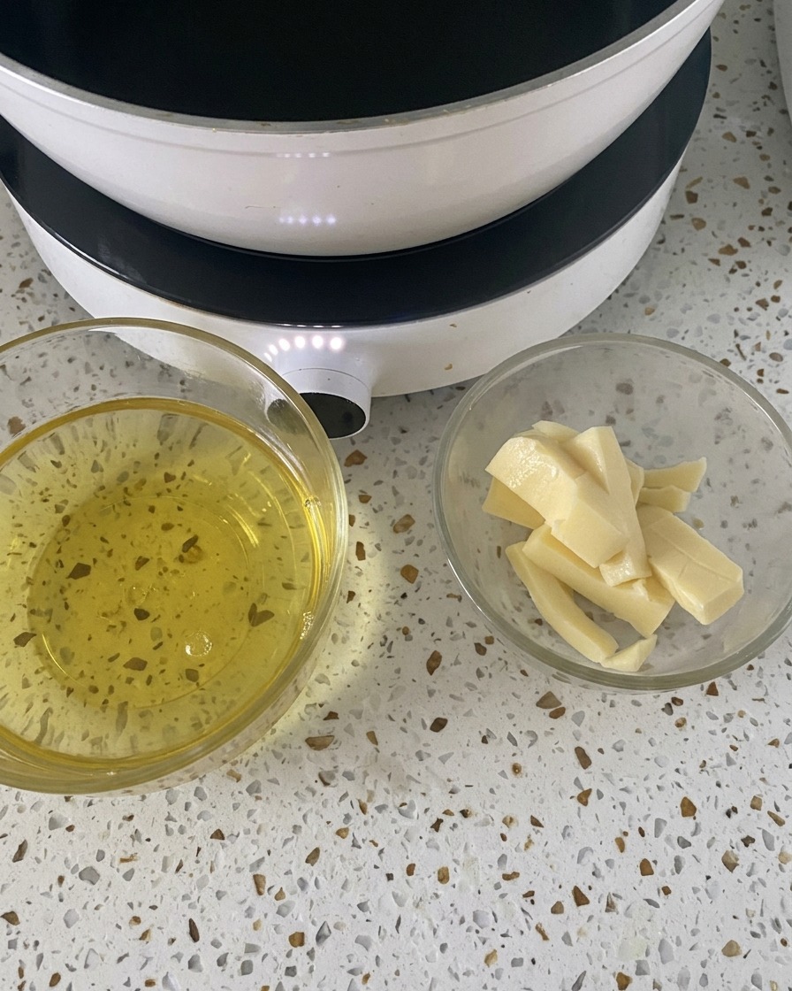 Two small glass bowls containing cracked eggs and sliced mozzarella cheese sitting on a white countertop next to a hotplate.
