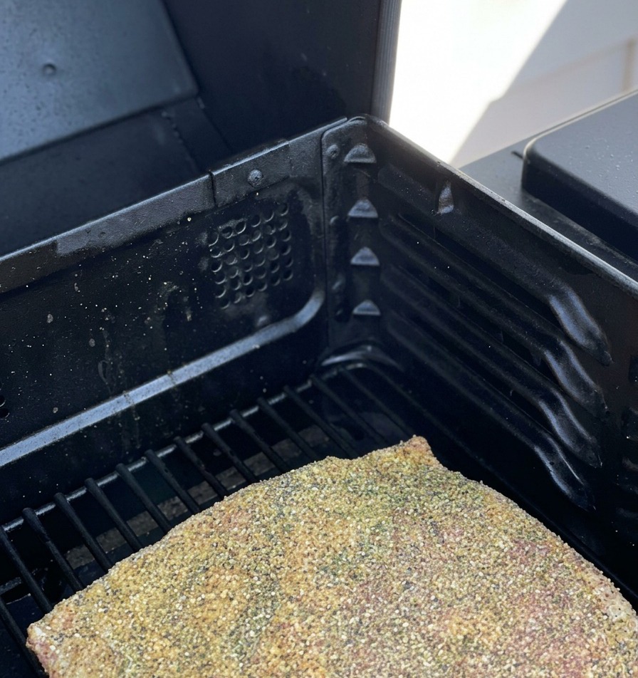 Seasoned raw beef ribs resting on the grates of a smoker.