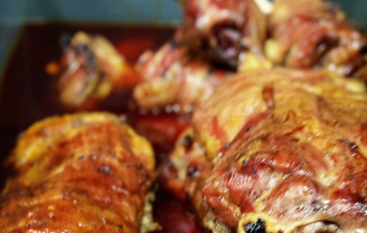 Several pieces of browned, smoked beef submerged in a deep reddish-brown liquid marinade inside a blue tub.