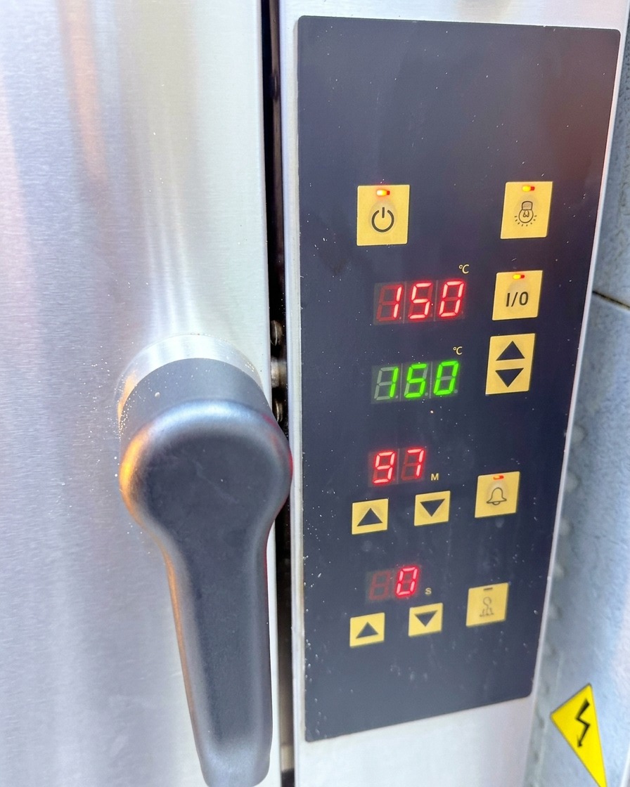 A stainless steel convection oven control panel showing a digital temperature reading of 150 degrees Celsius.