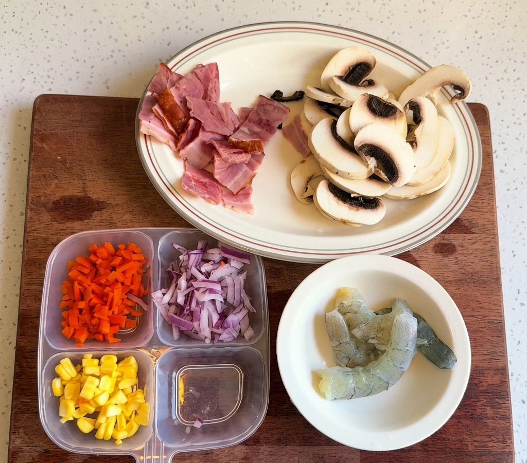 A plastic container holding separated sections of diced carrots, yellow corn kernels, and chopped red onions.