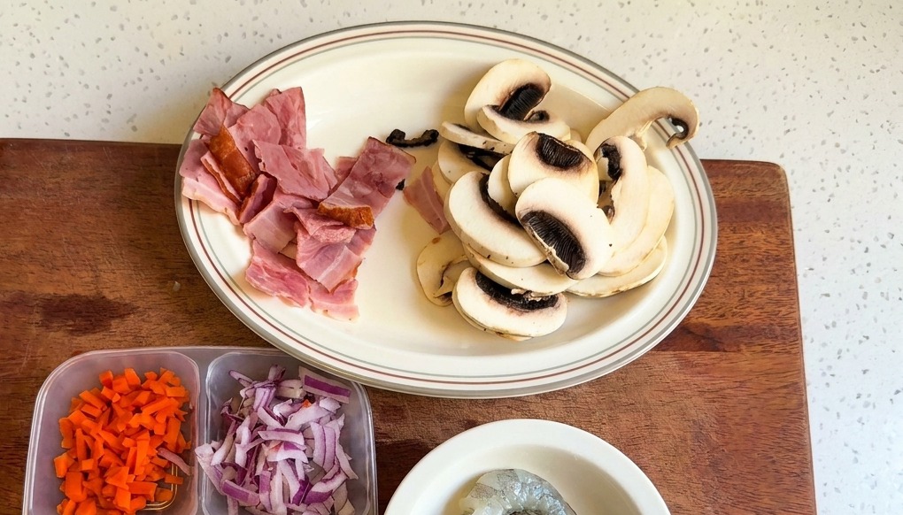 A white plate holding sliced white button mushrooms and chopped bacon pieces.
