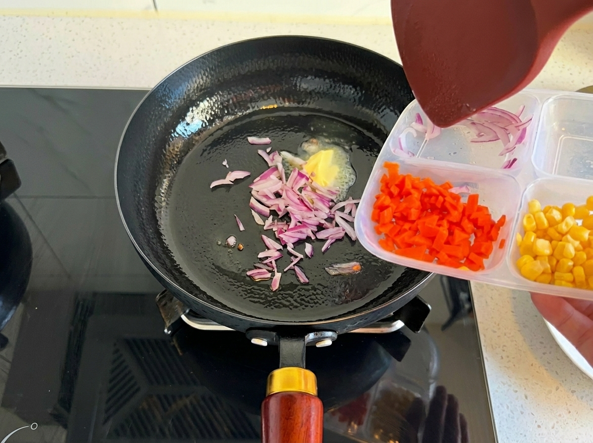 Chopped red onions being added from a container into a hot pan with melted butter.