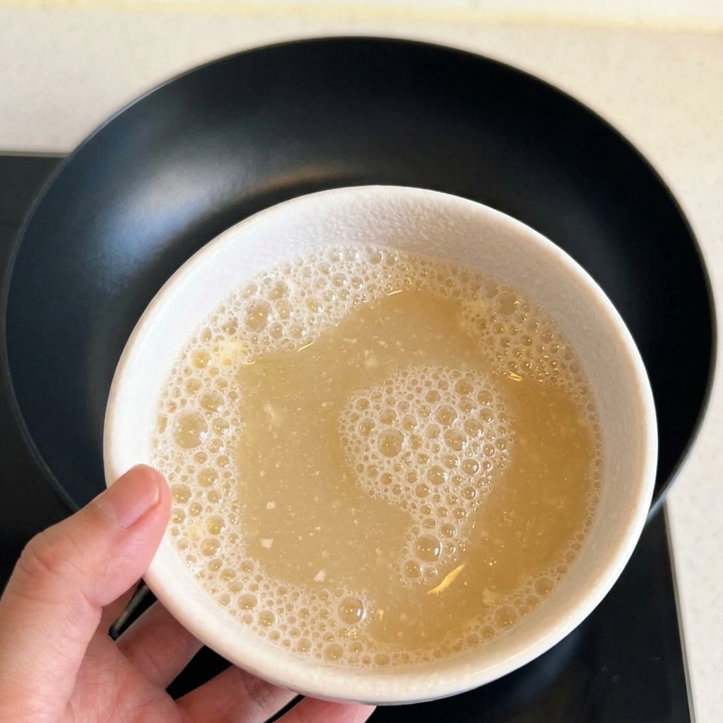 A bowl containing a mixed, frothy flour and water liquid.