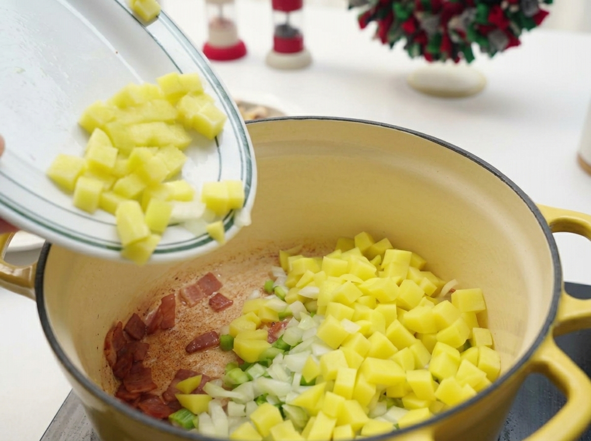 Diced potatoes, celery, and onions being transferred from a white plate into a pot with cooked bacon.