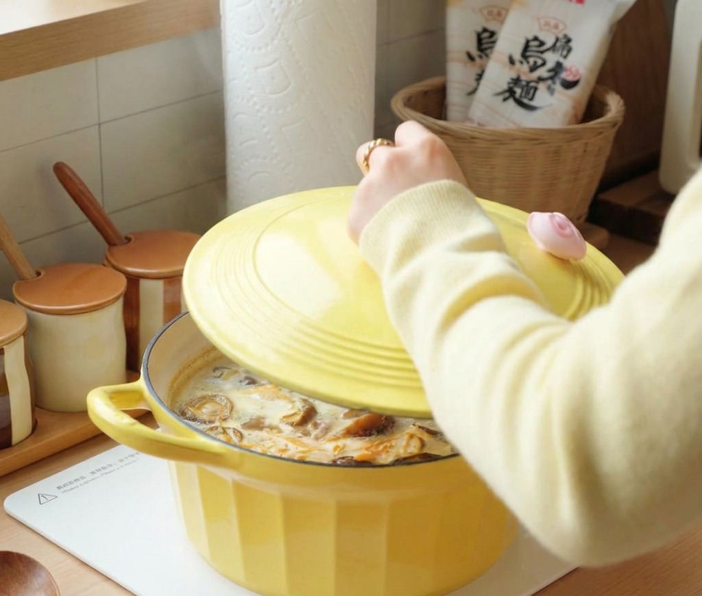 A person placing a yellow lid on a bubbling pot of chicken and mushroom soup.