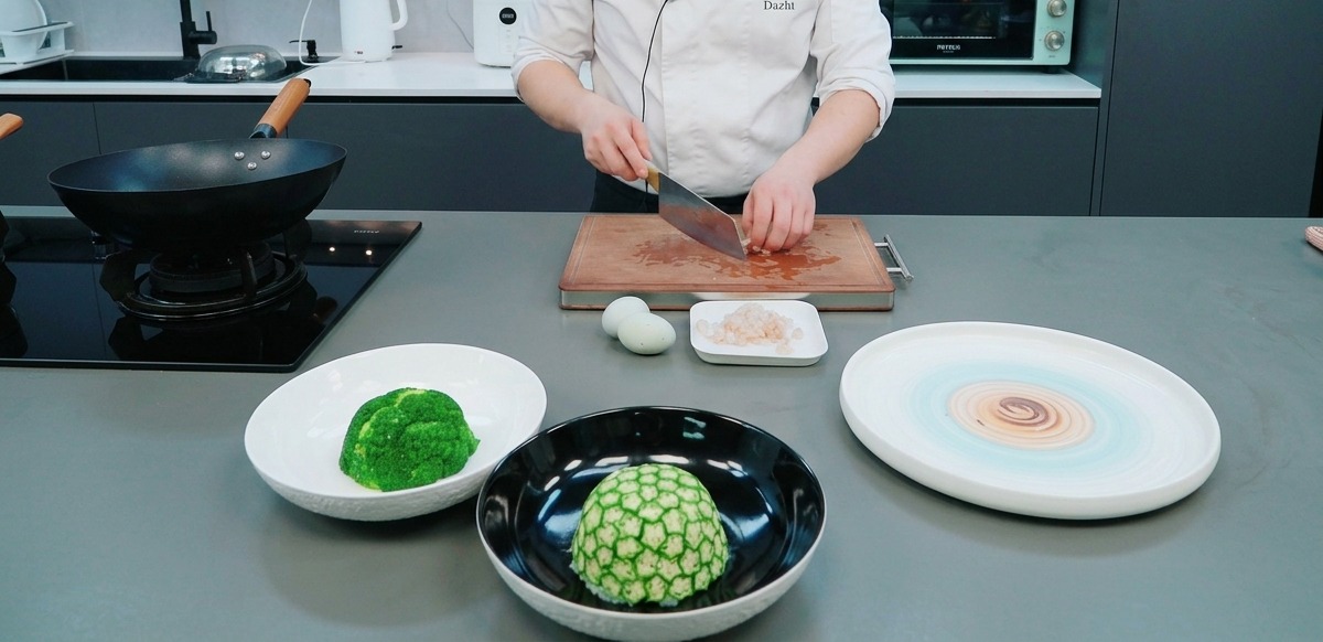 Hands using a cleaver to dice red preserved meat on a wooden cutting board, with prepared ingredients in the foreground.