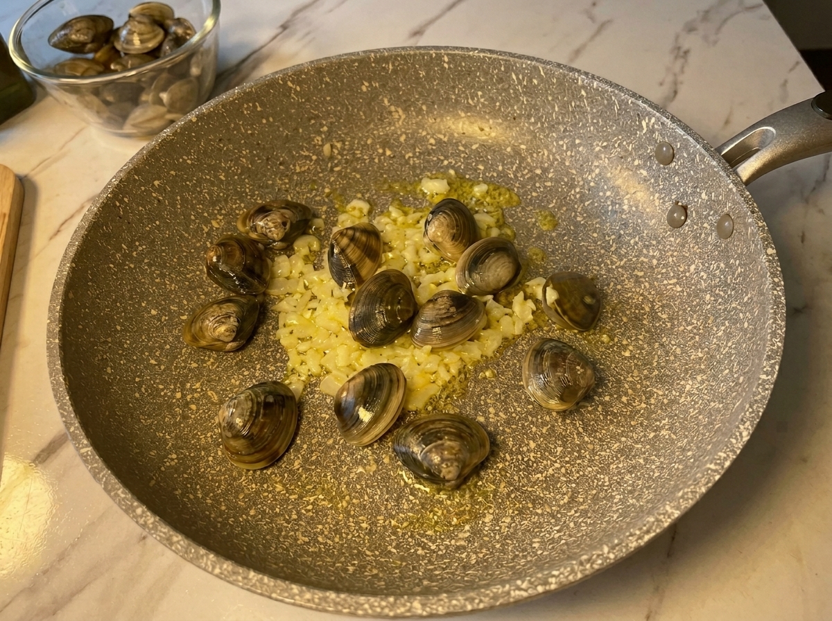 Fresh, closed clams added to a hot pan with sautéed minced garlic and onions.