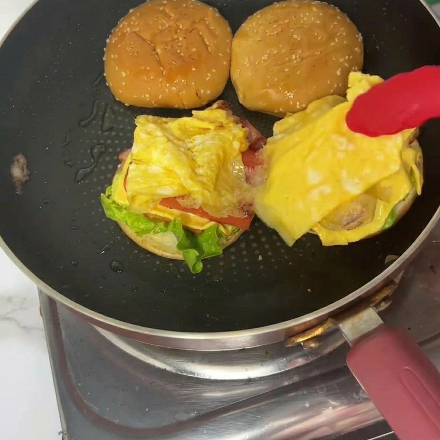 A finished breakfast burger on a plate with the toasted sesame top bun firmly in place.