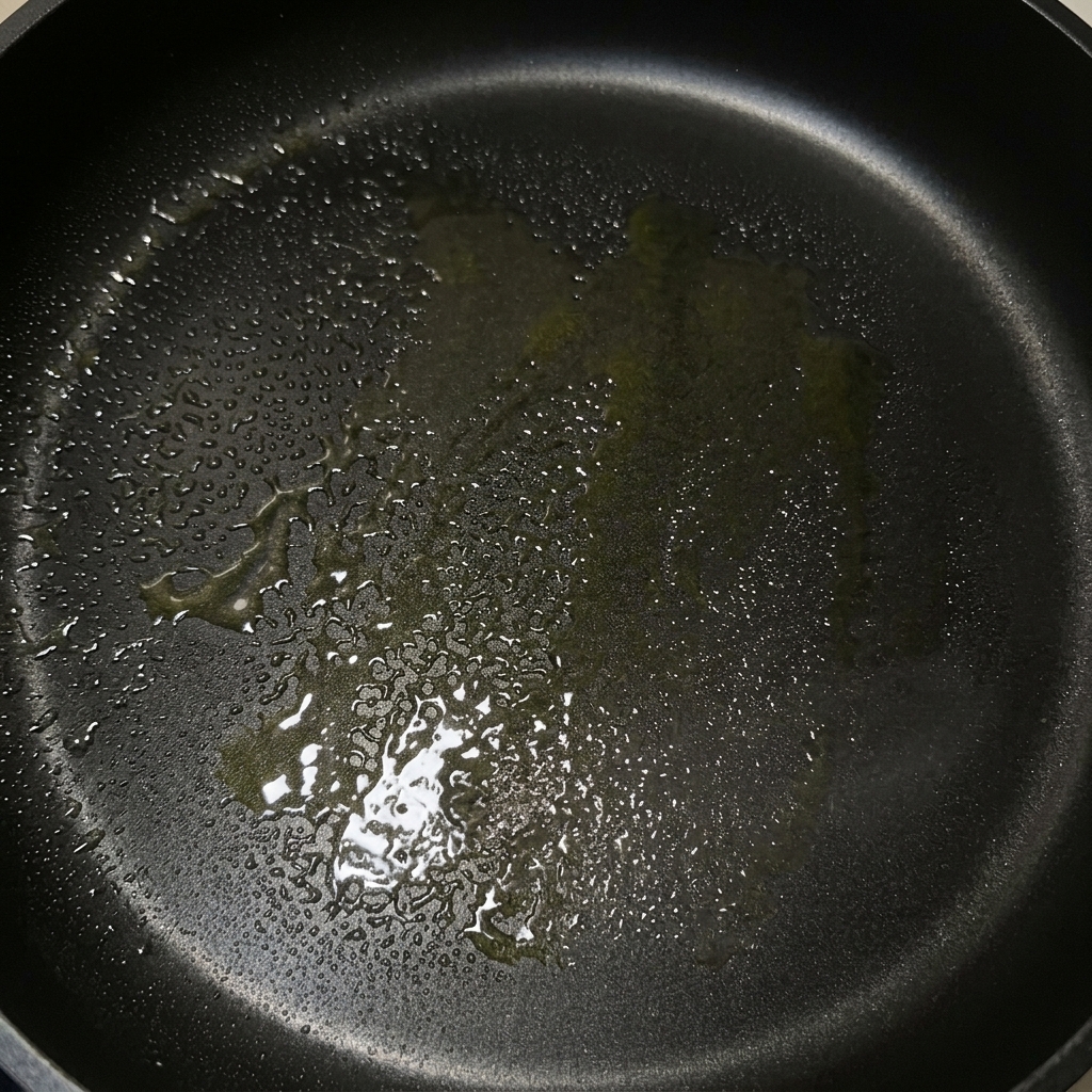 A black frying pan with a shimmering coating of melted butter and olive oil, ready for cooking.