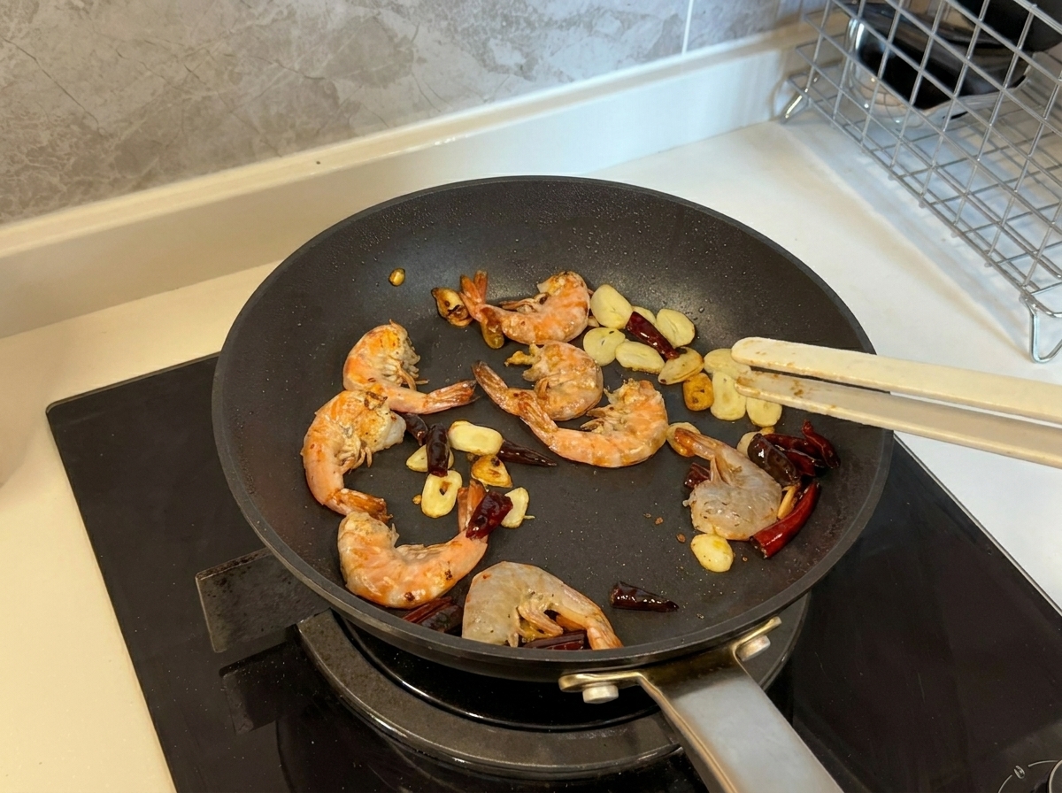 Shrimp turning pink and golden as they are pan-fried with garlic and chilies in a pan.