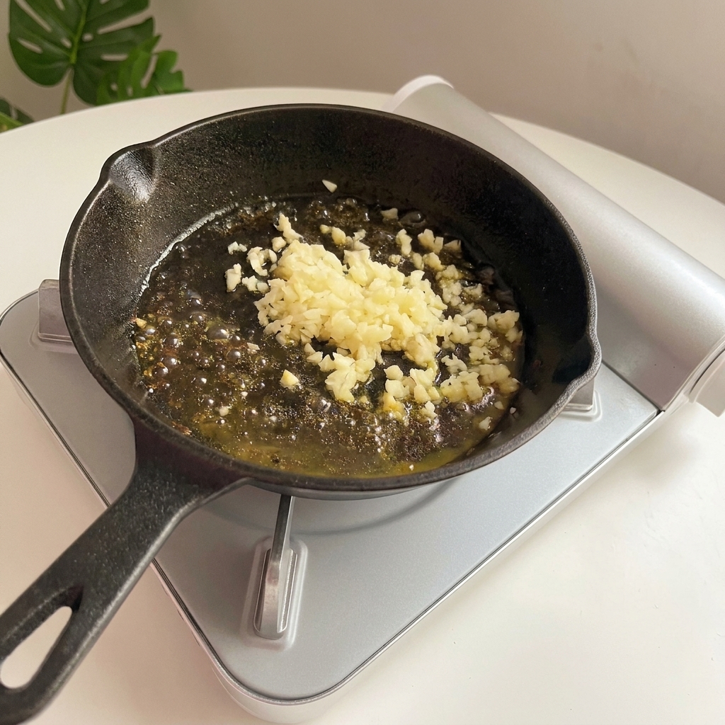 Minced garlic sizzling and turning golden-brown in melted butter inside a cast iron skillet.