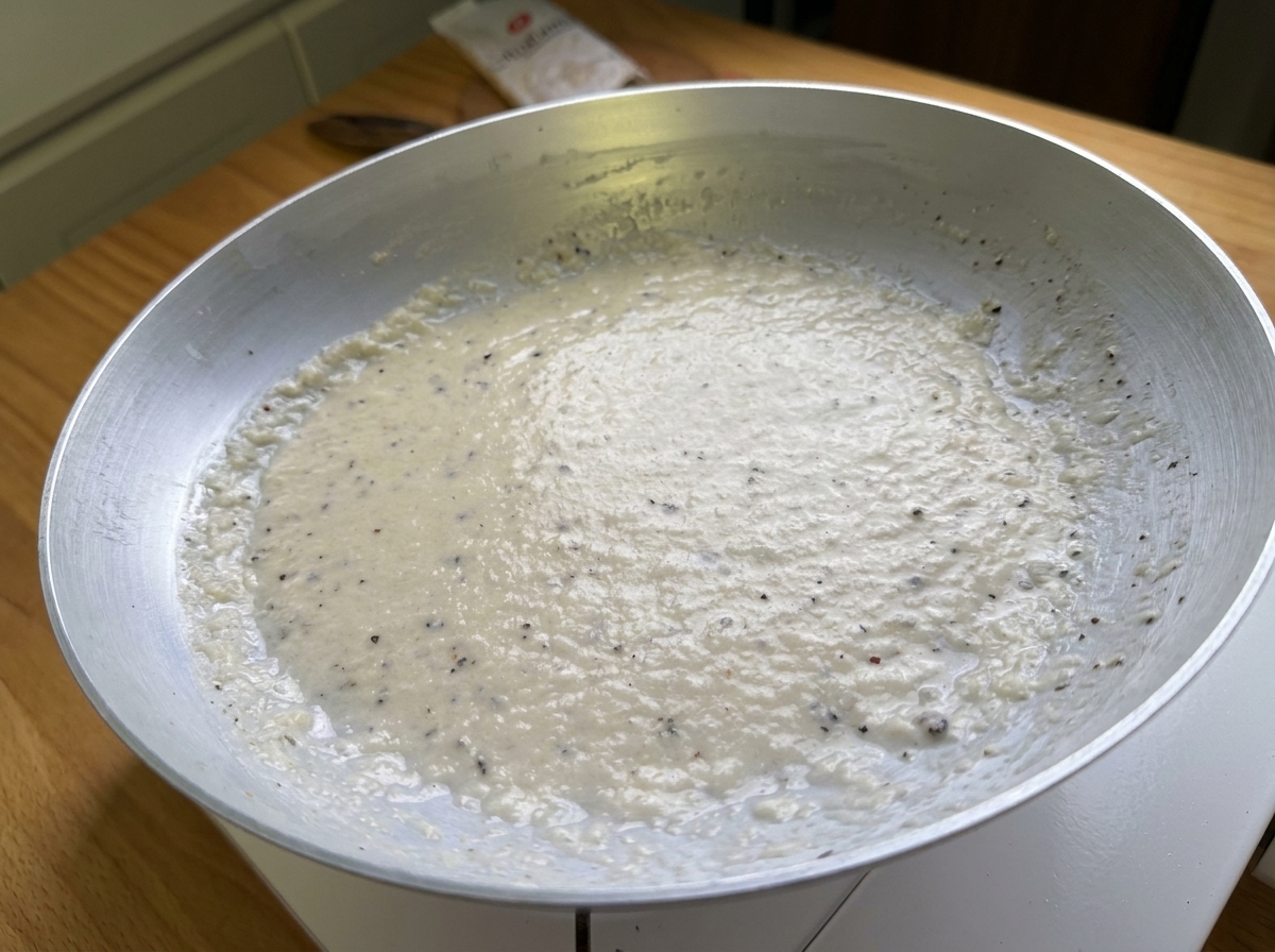 Close-up of a smooth, creamy paste made from Pecorino cheese and black pepper resting in a pan.