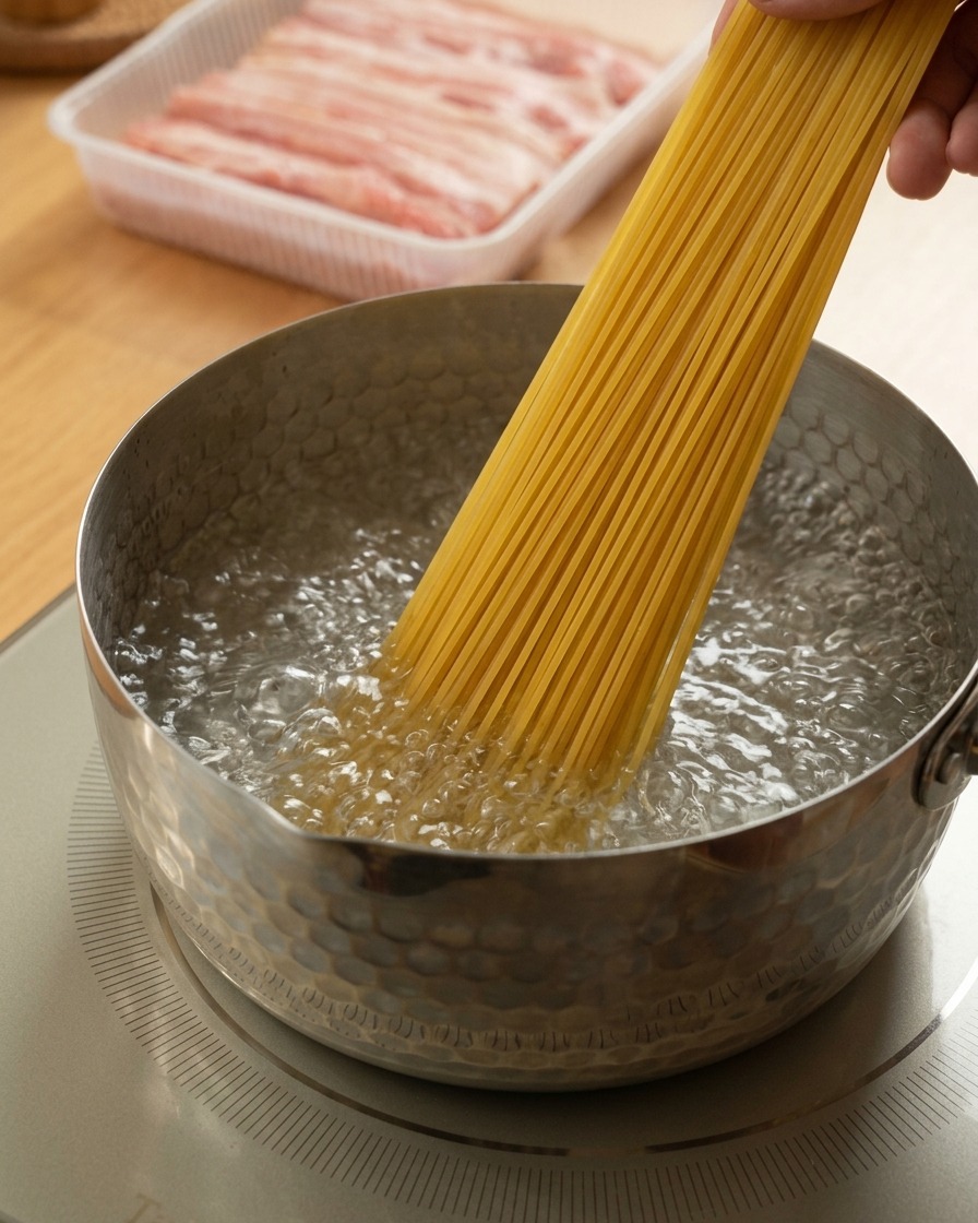 A hand placing a bundle of dry spaghetti into a saucepan of vigorously boiling water.