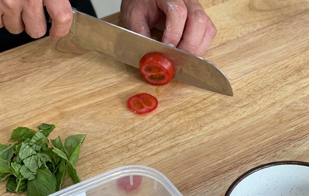 Slicing fresh cherry tomatoes on a wooden board.