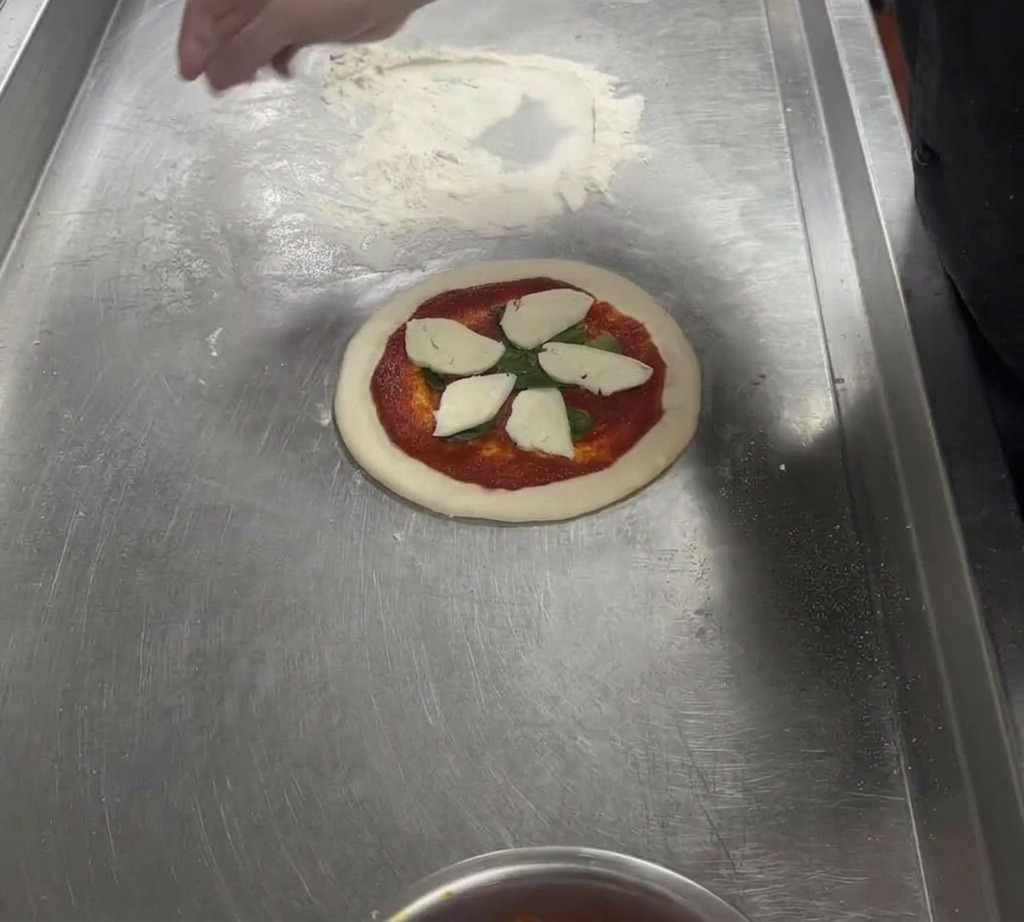 Thick slices of fresh white mozzarella cheese arranged in a star pattern on top of a sauced pizza dough.