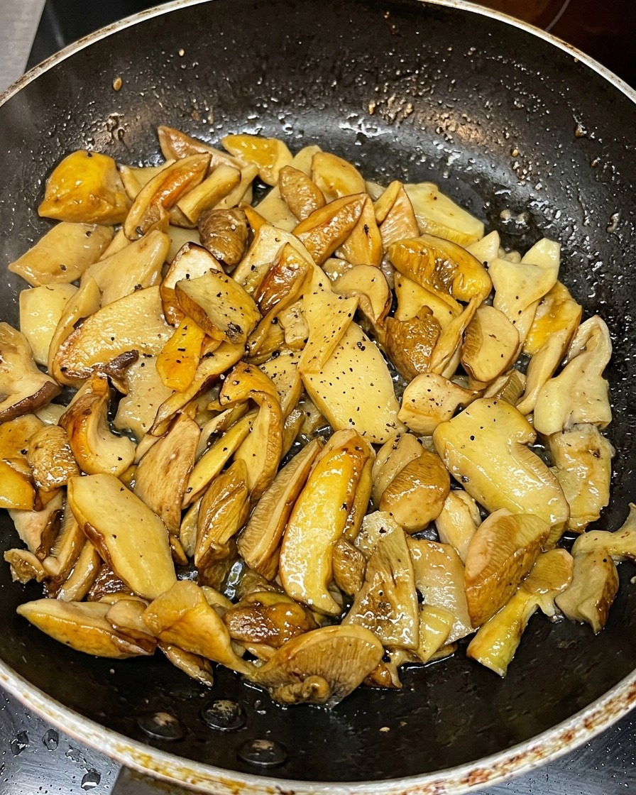 Golden-brown sliced mushrooms sautéing in a hot pan.