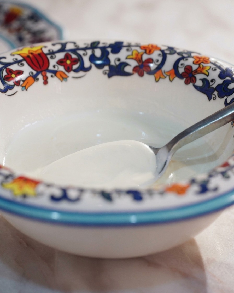 A spoonful of cream in a small decorative bowl, ready to be mixed with black truffle paste.