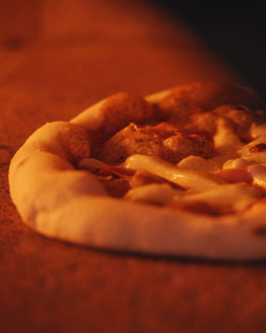Close-up of a bubbling Neapolitan pizza with a thick, puffy crust baking inside a hot, orange-glowing oven.