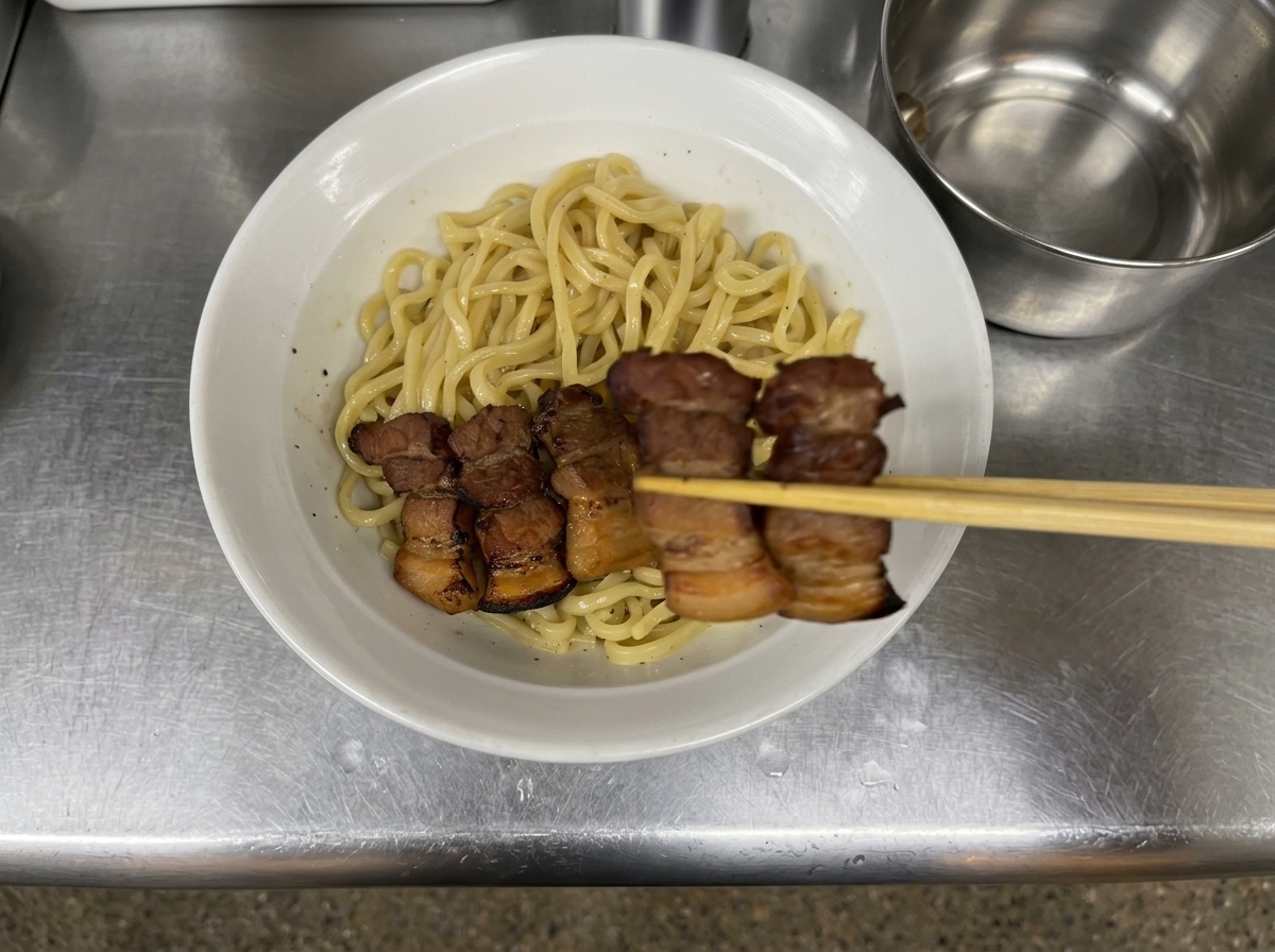 Chopsticks carefully placing slices of braised pork belly in a neat row onto a bed of sauced noodles.