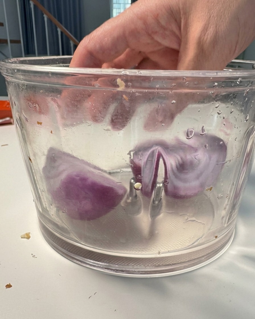 Chunks of purple onion inside a food processor bowl ready to be blended.