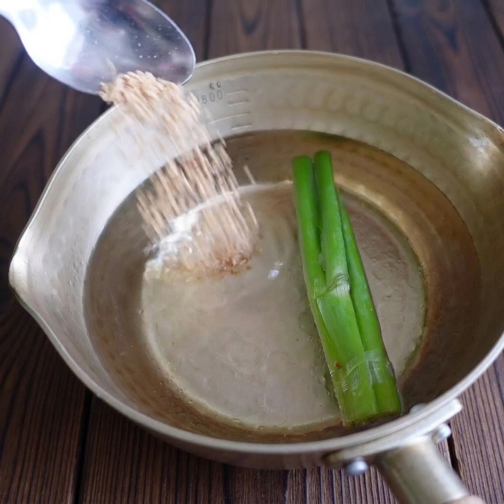 A metal spoon sprinkling granular chicken bouillon powder into a pot with water and green scallions.