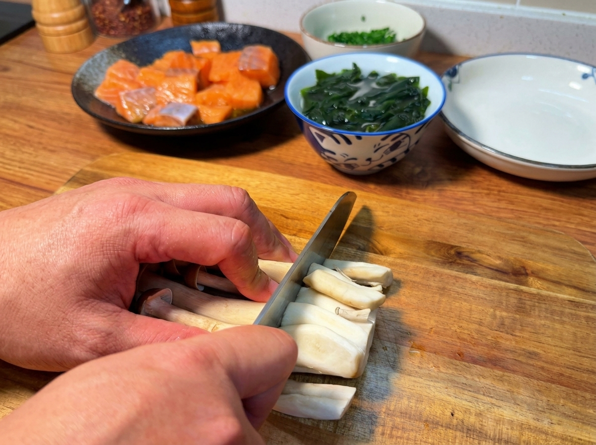 Hands slicing the root ends off brown beech mushrooms on a wooden cutting board.