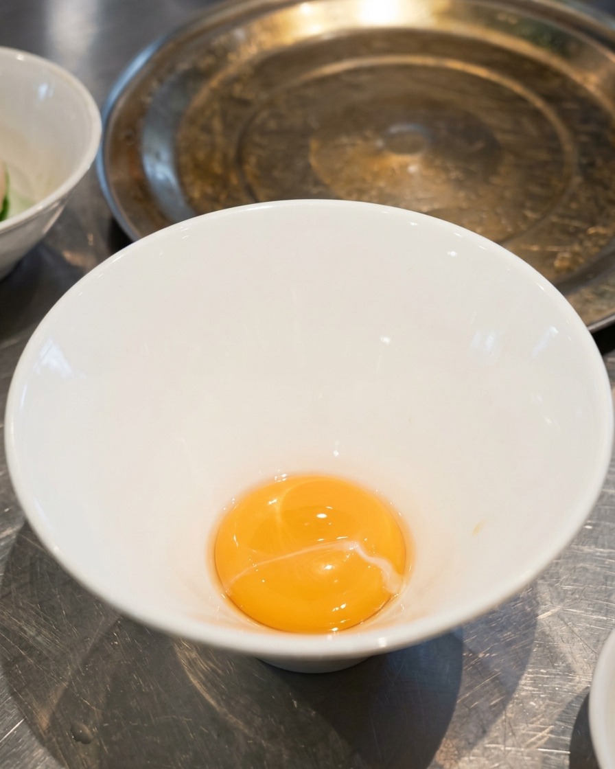 A small amount of golden yellow salt tare sauce resting at the bottom of an empty white ceramic ramen bowl.