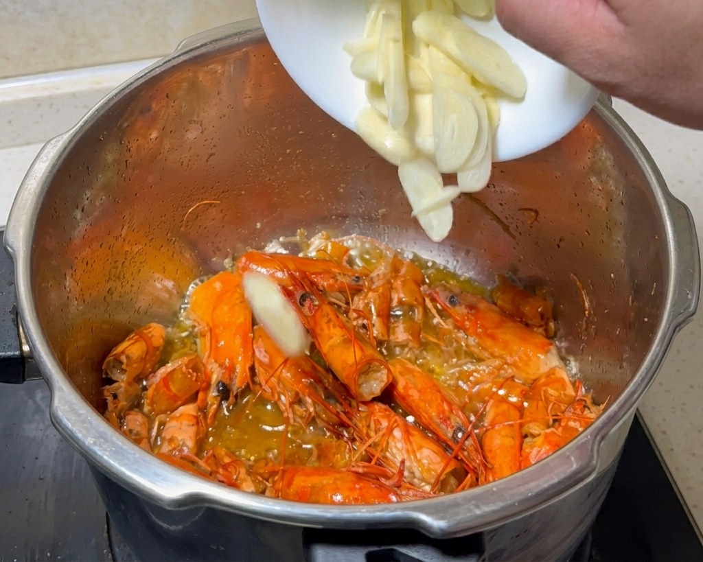 Freshly sliced garlic being added from a small white bowl into the pot with fried shrimp shells.
