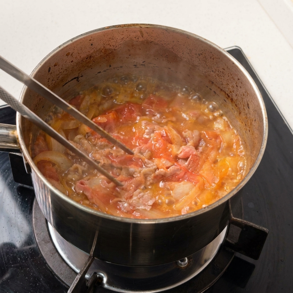 Thinly sliced beef and onions simmering gently in a shallow pool of dark savory liquid.