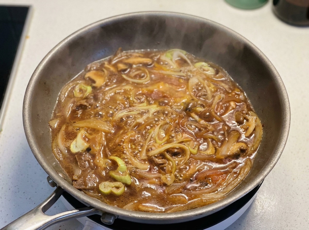 Beaten eggs being swirled into a pan of simmering sauce scallions and red onions.