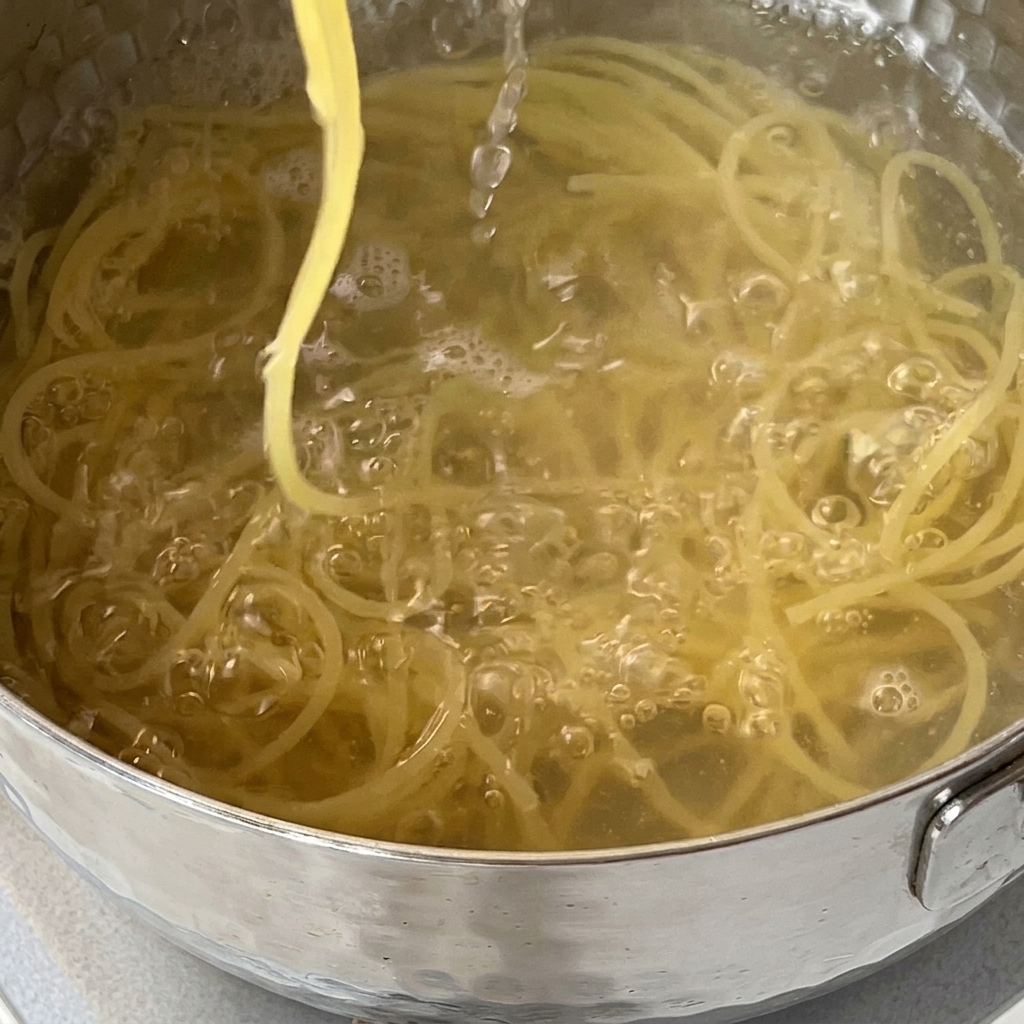 Spaghetti being drained into a colander in a kitchen sink.