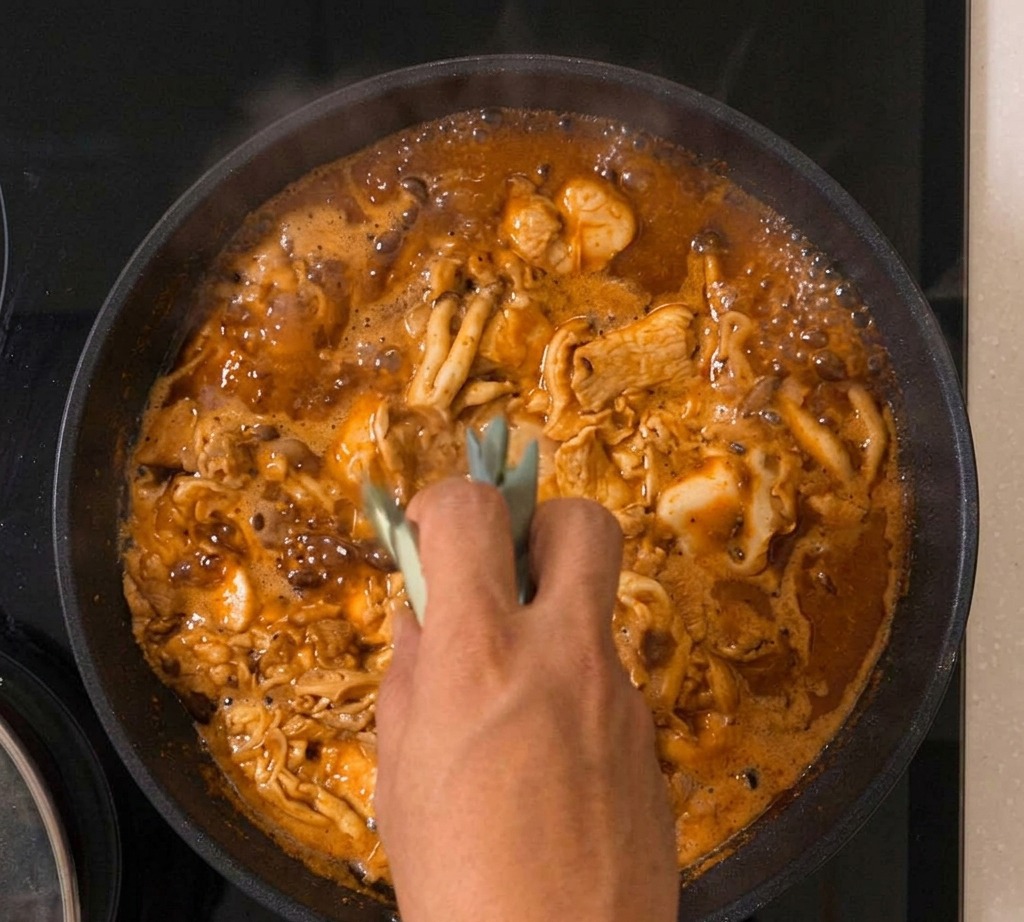 The Oyakodon mixture bubbling in a pan with green onions visible amongst the setting egg and chicken.