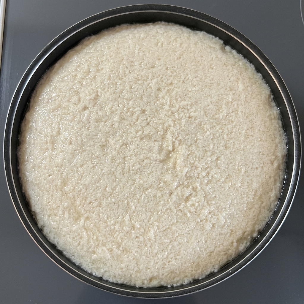 A circular sheet of textured oil-absorbing paper floating on top of water in a black pot to remove cooking scum.