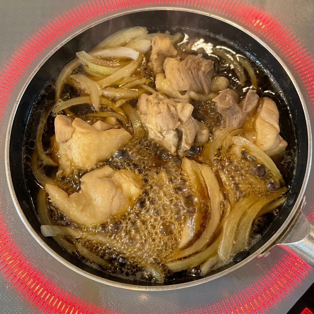 Beaten egg wash being poured from a bowl into a pan over chicken and onions