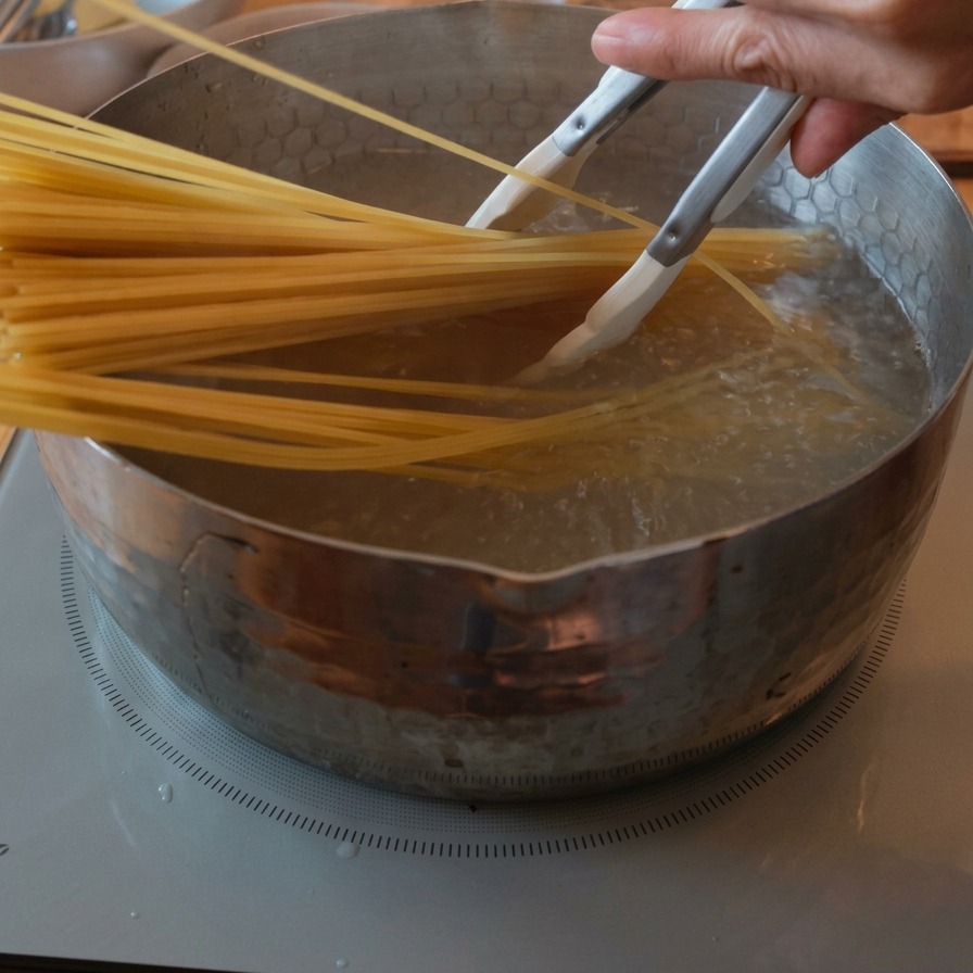 A bunch of dry spaghetti being submerged into a pot of bubbling, boiling water using tongs.