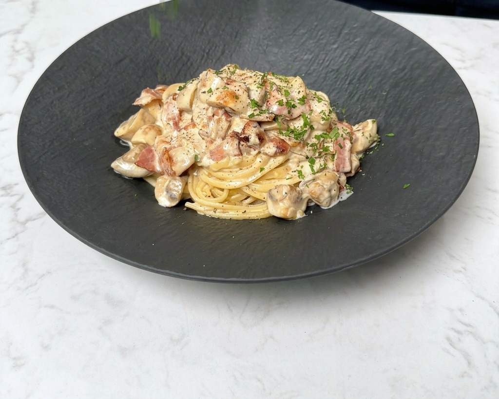 Sprinkling freshly chopped green parsley over a steaming plate of creamy bacon and mushroom pasta.