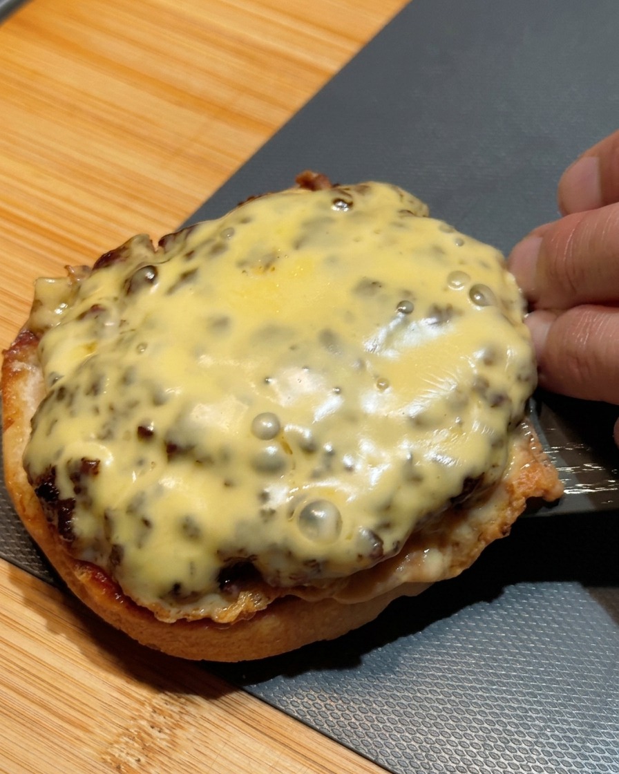 A spatula transferring two stacked beef patties covered in melted cheese onto a bottom bun.