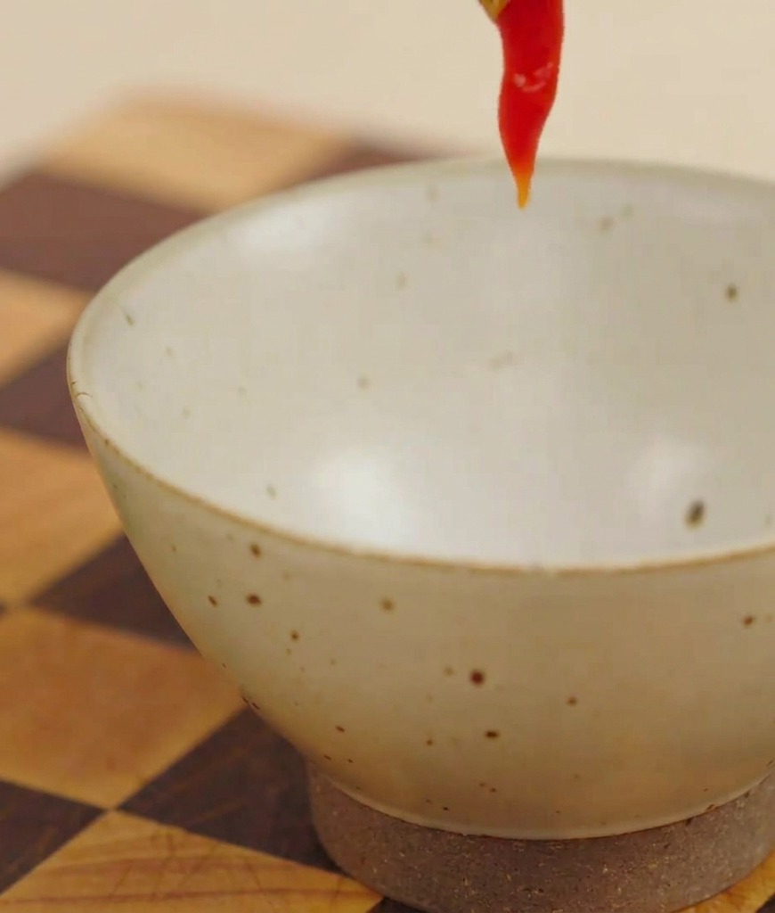 Red ketchup being squeezed into a small bowl to make a burger sauce.