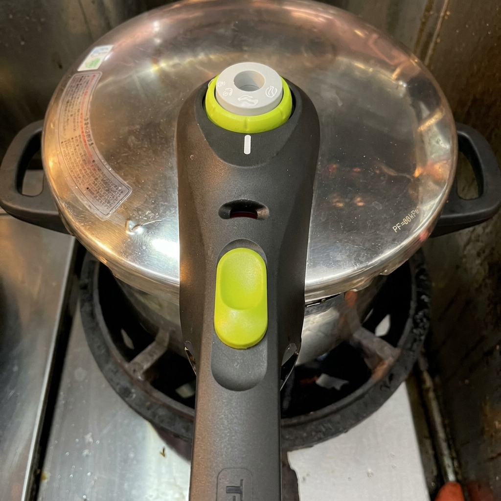 A stainless steel pressure cooker with its lid securely locked in place, sitting on an active stove burner.