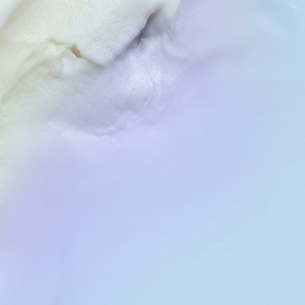 A close-up of a wooden spatula stirring a thick, creamy white sauce in a pot.