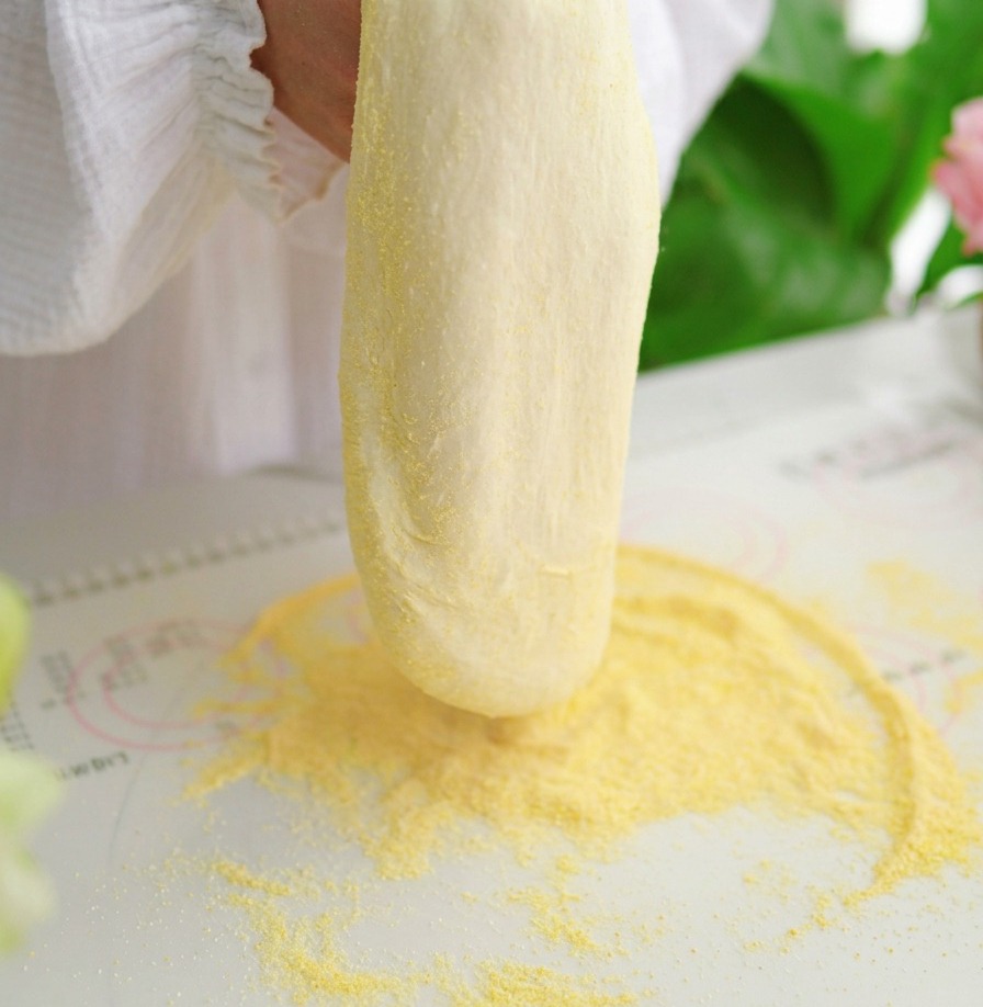 Pizza dough being held vertically and stretched by hand over two fists against a white background.