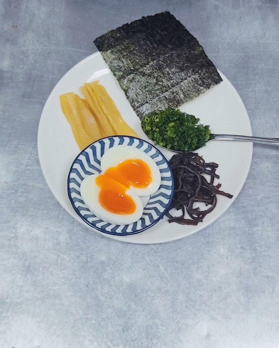 Two circular slices of marbled, braised chashu pork placed in the center of a clean white plate.