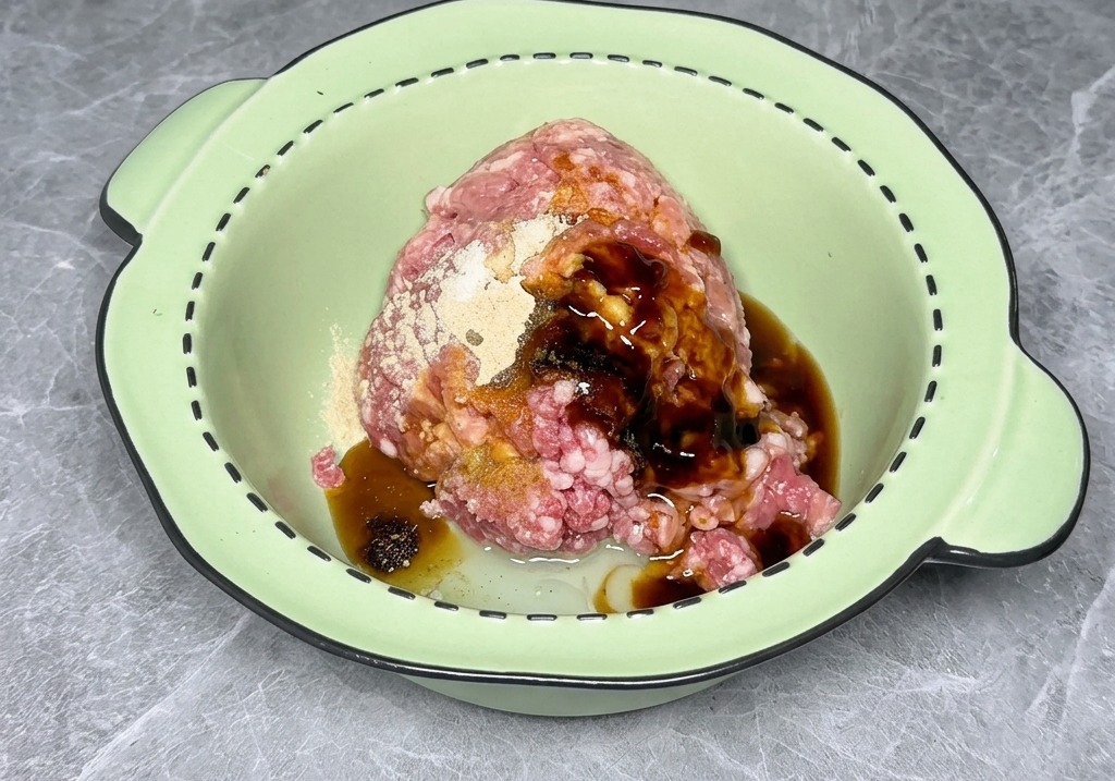 Ground meat in a light green bowl surrounded by soy sauce and various dry seasonings before being mixed.