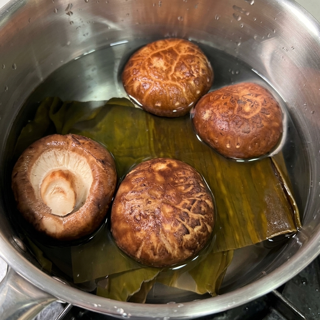 Dried kombu and brown shiitake mushrooms soaking in a small pot of clear water.