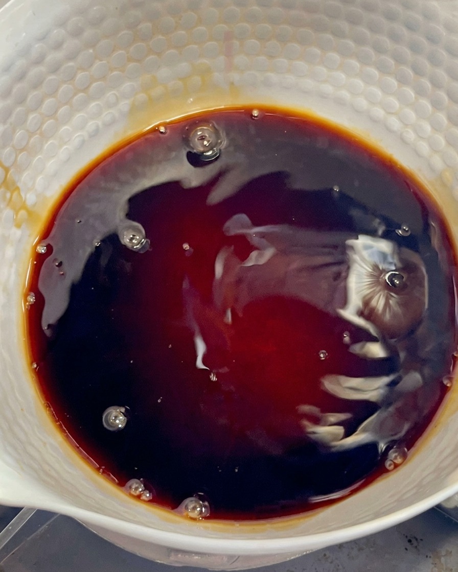 A dark, glossy mixture of Japanese soy sauce and mirin resting in a white potcite: 60.