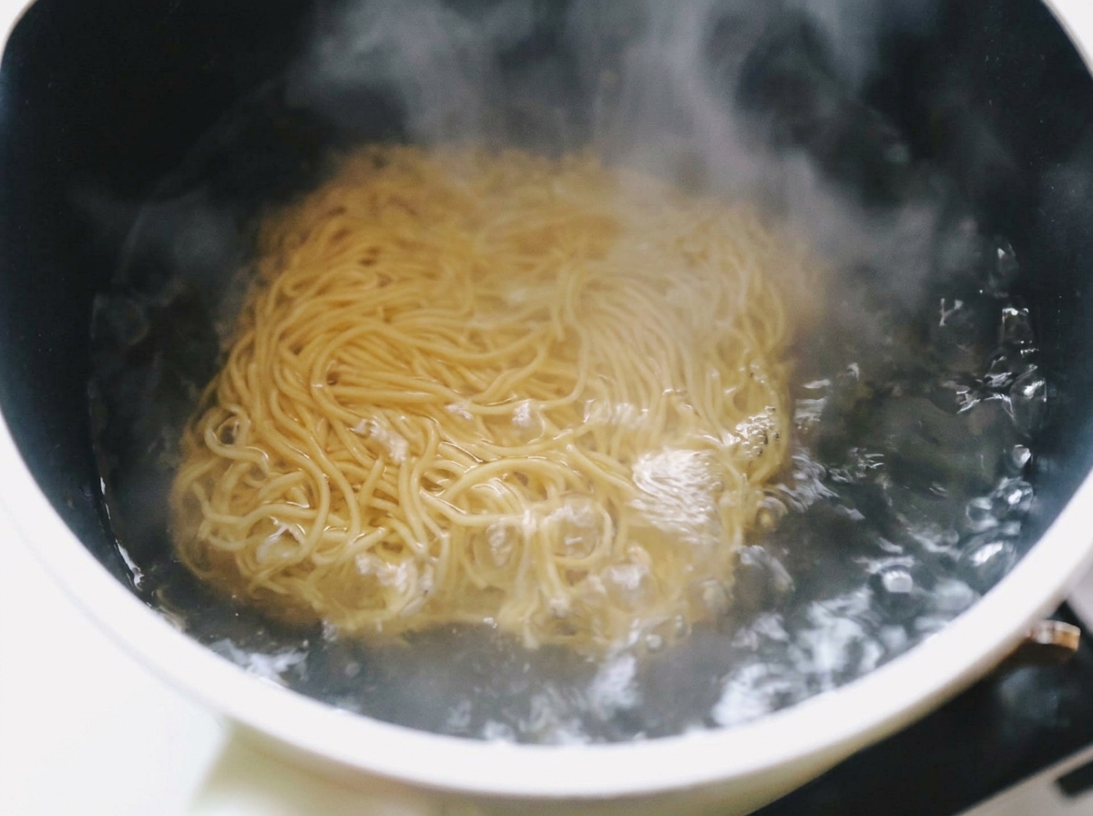 Wavy instant ramen noodles submerged in a pot of rapidly boiling water with steam rising.