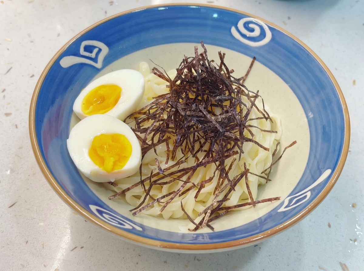 A finished bowl of Tsukemen noodles topped with shredded nori and sliced soft-boiled eggs.