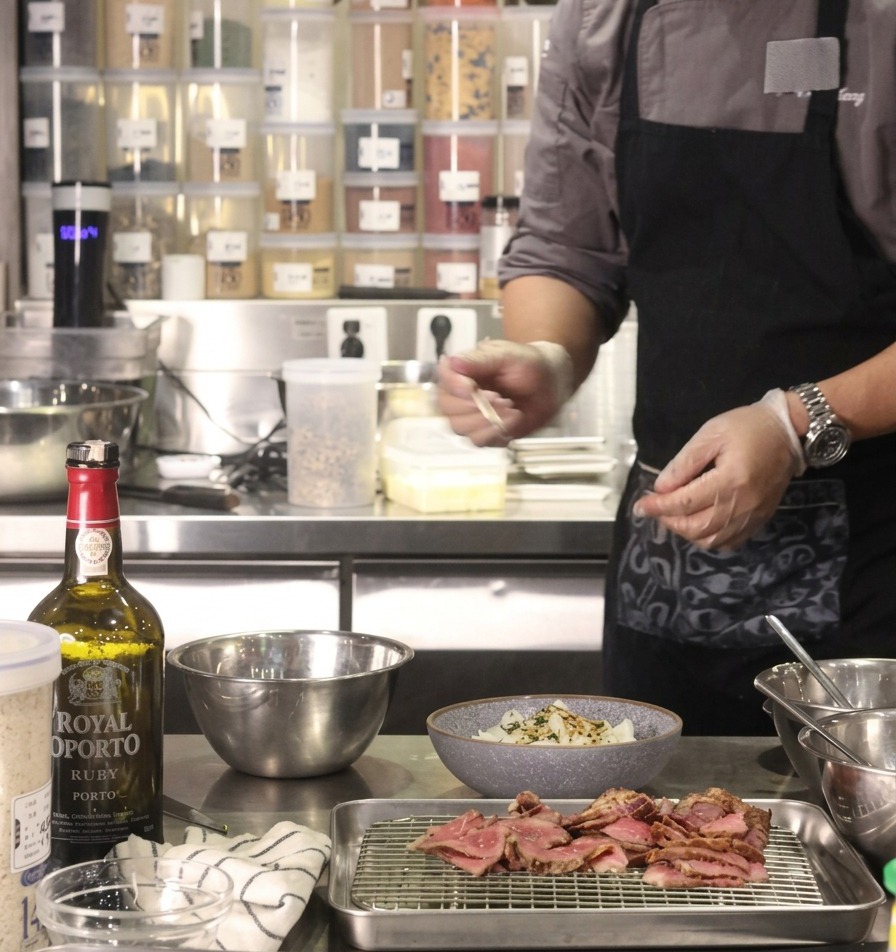 A chef adding a portion of golden caramelized onions to the middle of a prepared rice bowl.