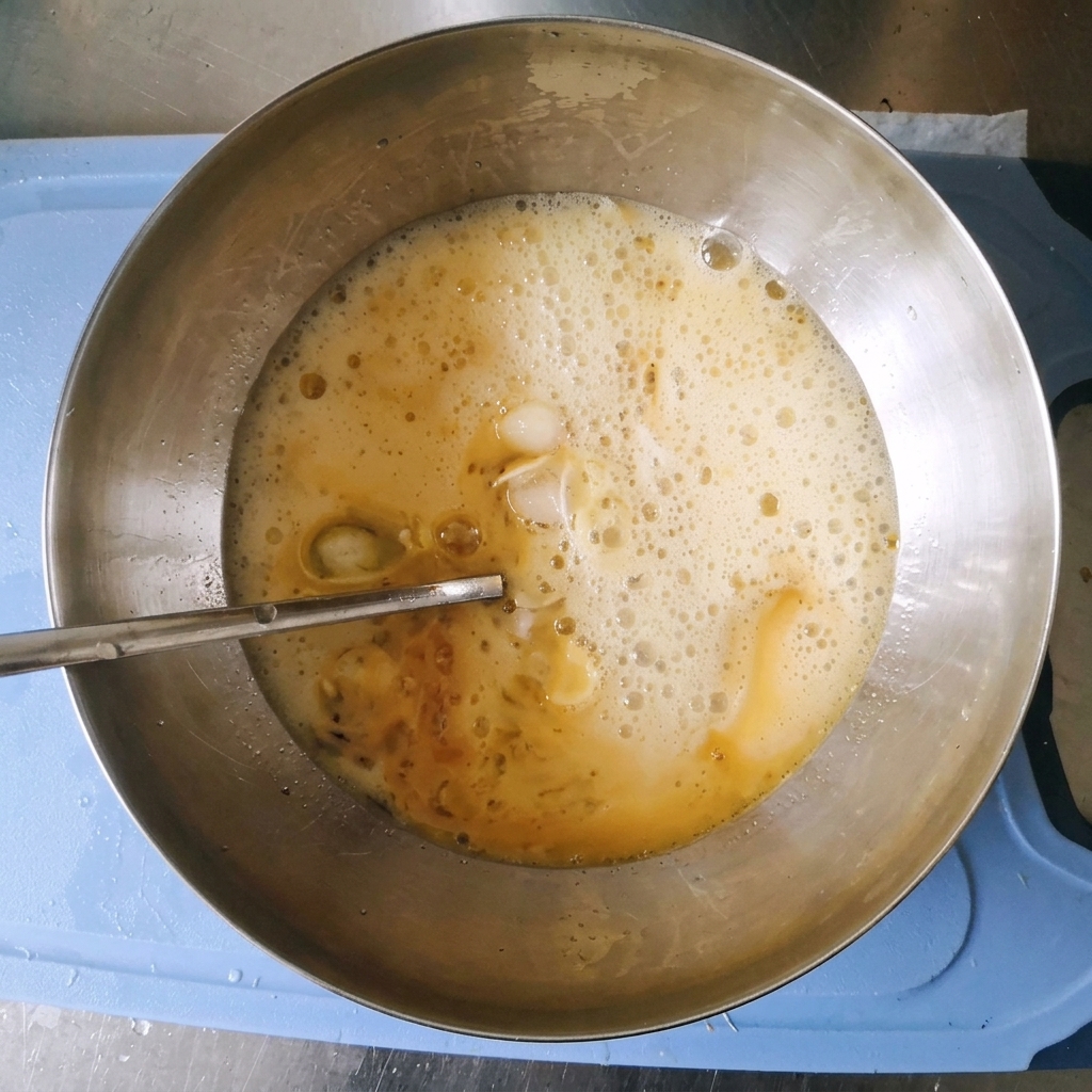 A bubbly, foaming marinade mixture inside a stainless steel mixing bowl after carbonated water has been added.